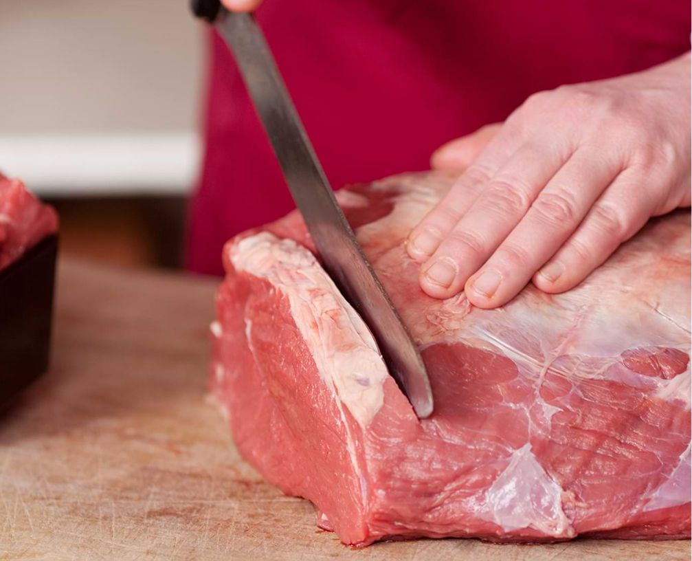 Ein Metzger schneidet ein Stück Fleisch